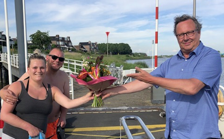 Bloemetje voor eerste passagier zomervaart pontje Vrevia