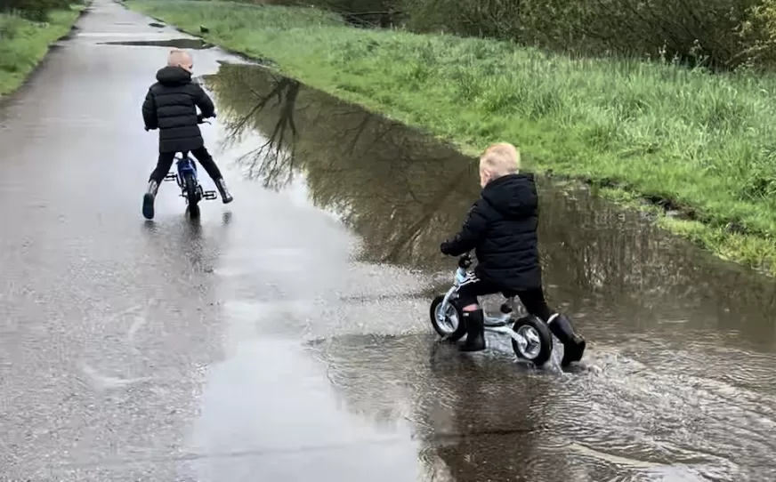Kinderen op fietsje door plas