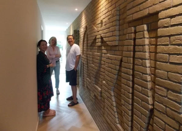 De familie Chen met familie van Dora Tuynman bij het baksteenreliëf in de gang van het woonhuis aan de Klaverkamp in Vreeswijk, Nieuwegein. Foto Door Jelsma