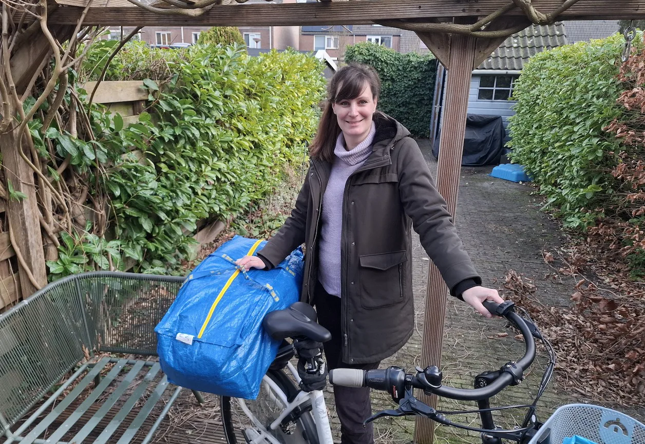 Elvira met een kleidingtas voor de kledingketting