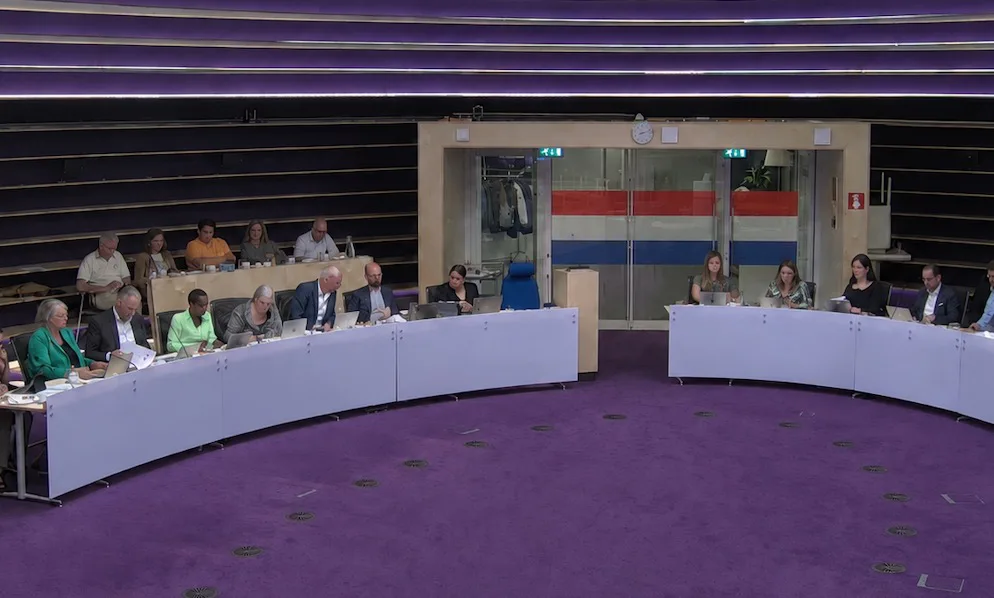 Raadszaal met nederlandse vlag in glazen deur